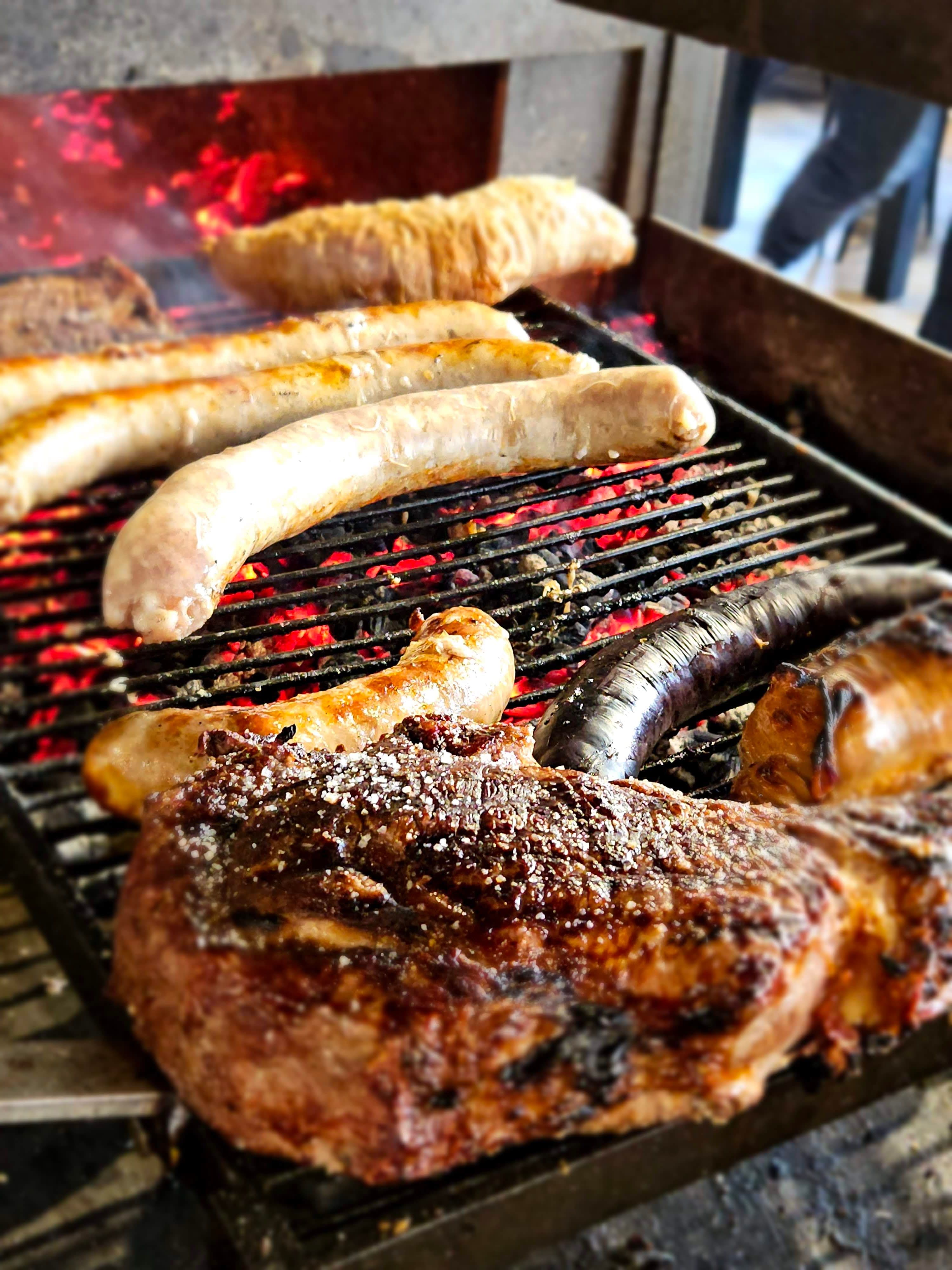 Grillades au feu de bois : saucisses, boudin et viande grillée sur braises rouges au restaurant Table 23 à Carquefou